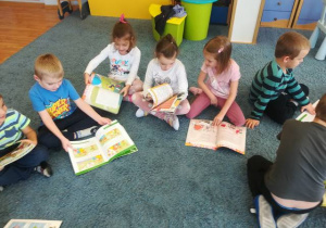 Dzieci na dywanie oglądają czasopismo „Świerszczyk”.